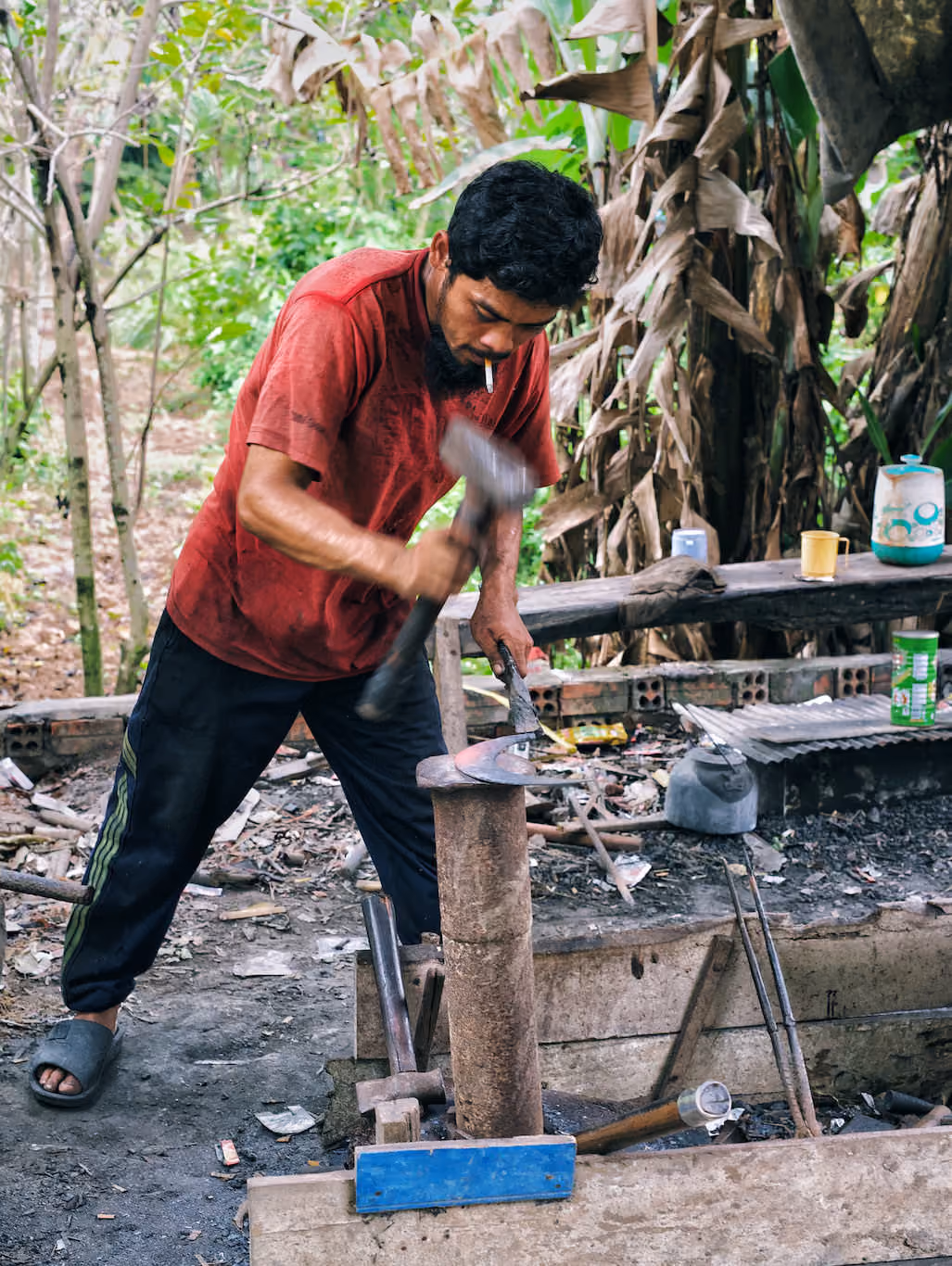 Cambodian blacksmith hammering a sickle