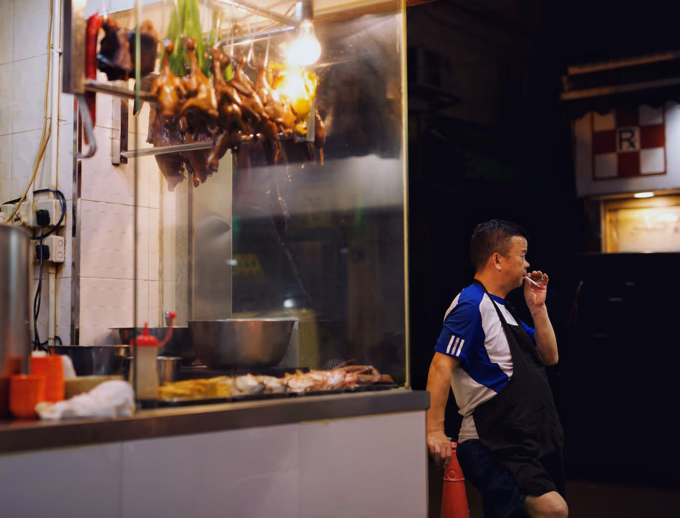 Man smoking outside of his restaurant at night in Hong Kong
