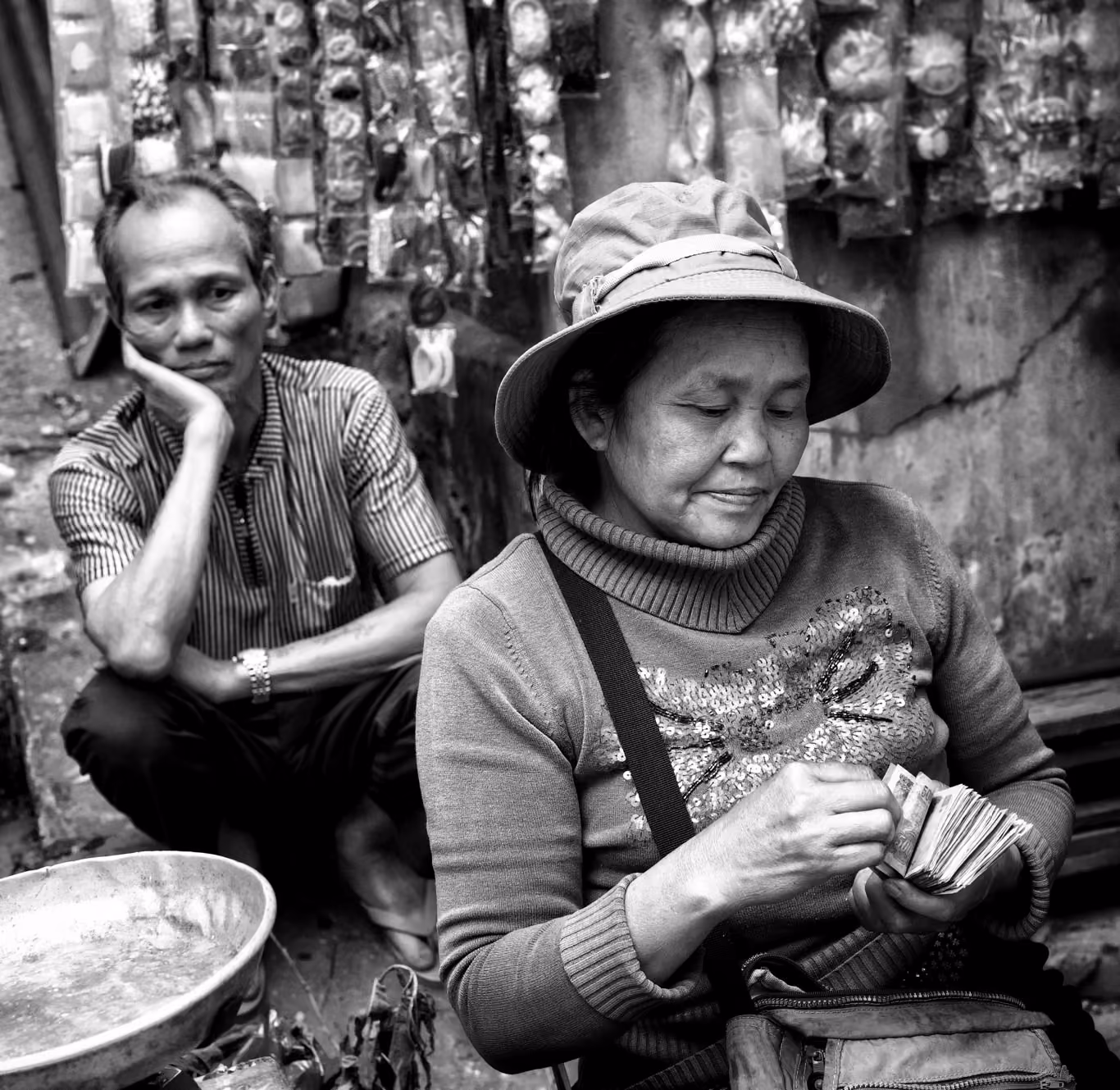 Vietnamese woman counts money while husband watches