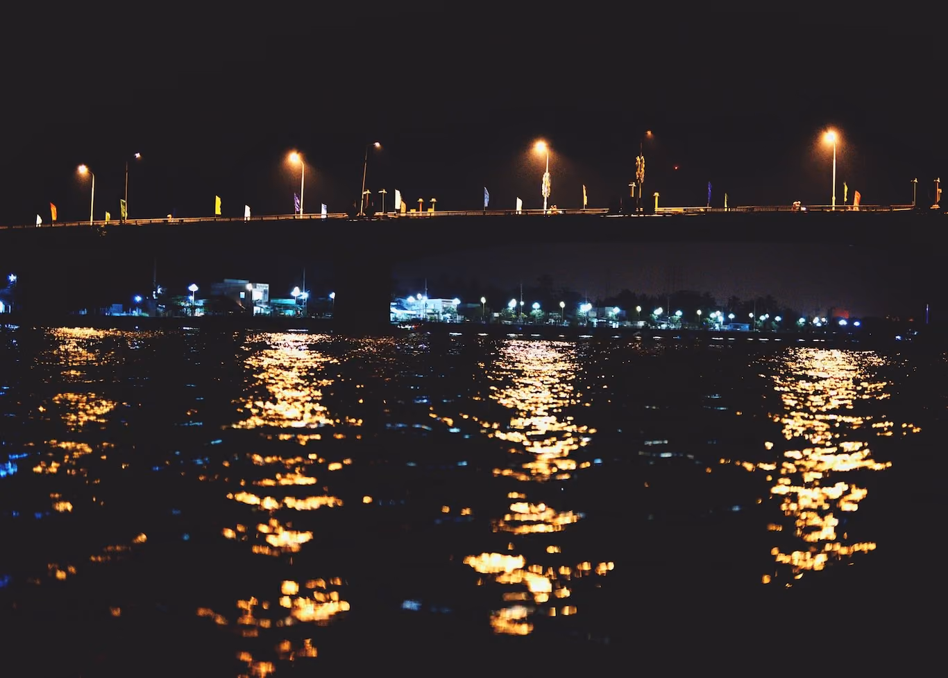 View of lighted bridge from the water in Vietnam